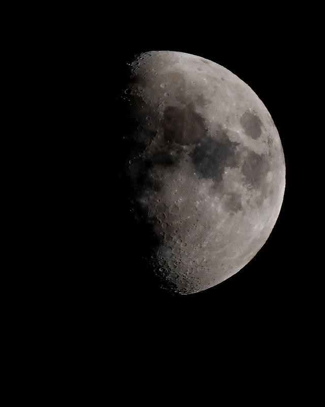 Waxing gibbous moon in cool silver tones showing dramatic terminator line and crater detail